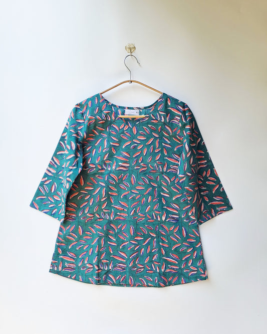 Green dress with pink leaf pattern on a hanger against a white background